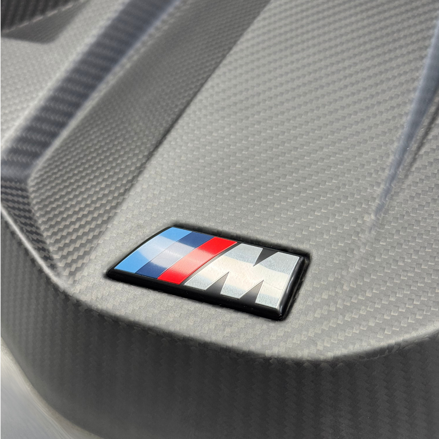 BMW logo on a carbon fiber-textured surface