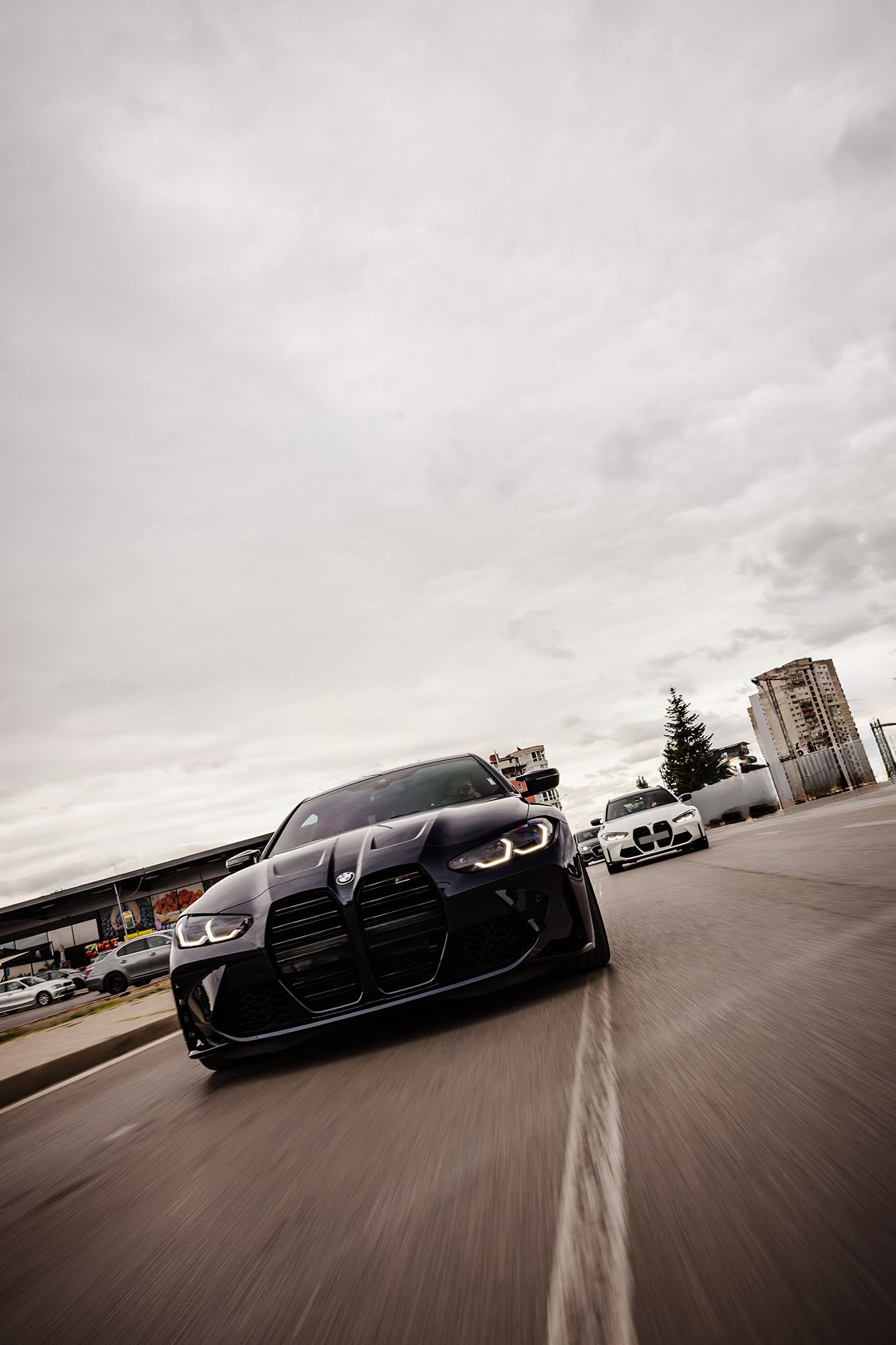 Black sports car driving on a road with a cloudy sky
